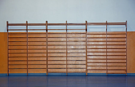 wooden wall bars for the exercises of athletes within a school gym