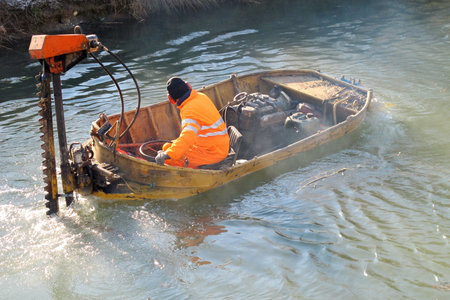 boat for River Cleanup and a worker with a yellow suit at work