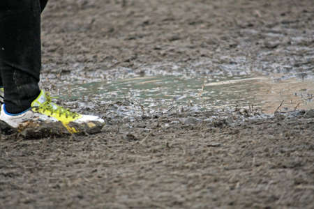 muddy soccer shoes of a child player during a football match in a playing field full of mudの写真素材