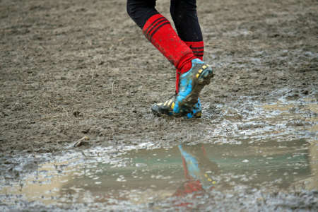 muddy soccer shoes of a child player during a football match in a playing field full of mudの写真素材