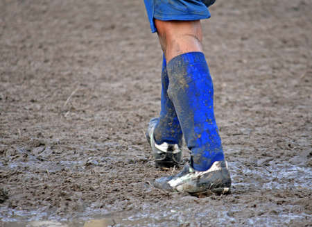 muddy soccer shoes of a child player during a football match in a playing field full of mudの写真素材
