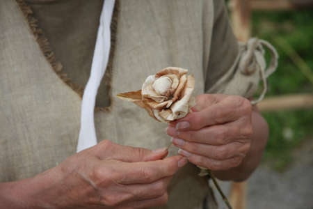hands of an elderly woman while creating a wooden flowerの写真素材