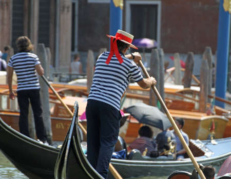 skilled Venetian gondolier while he drives his gondola on the Grand canal in Veniceの写真素材