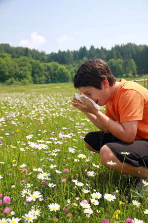 child with an allergy to pollen while sneeze in the middle of the flowersの写真素材