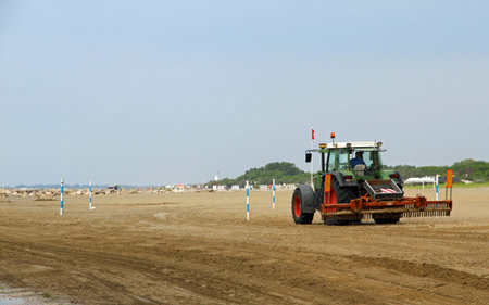 powerful tractor cleans the beach after a storm before the arrival of tourists