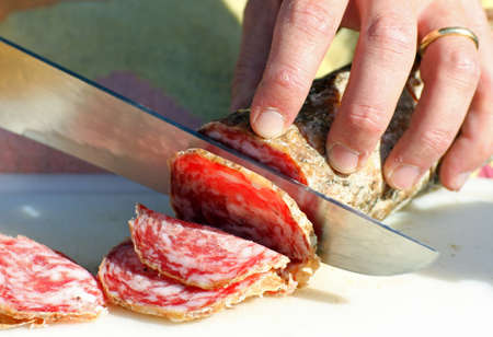 salami sliced by butcher's hands in the shopの写真素材