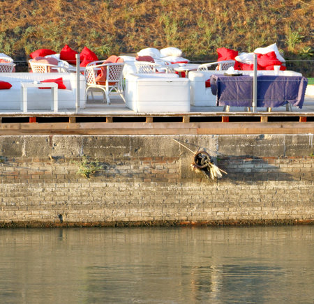 tables with red cushions of a restaurant on the shores of the riverの写真素材
