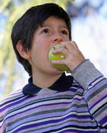 boy in striped wool sweater purple bite with hunger a green apple