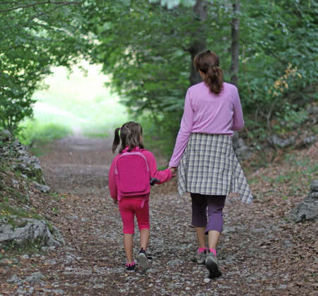 mom and daughter holding hands walking in the middle of the forestの写真素材