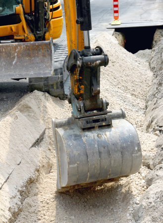big bucket of a bulldozer during the digging in the road in the city