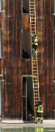 two firefighters with big ladder during a practice session in the Firehouseの写真素材