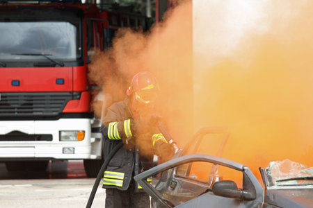 Firefighter  uses a hydrant toward a car with smoke