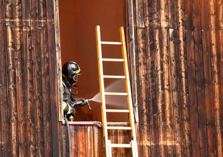 fearless firefighter with hydrant delivers plenty of water when switching off a fire in a Houseの写真素材