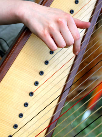pretty female hand while plucking the strings of a harpの写真素材