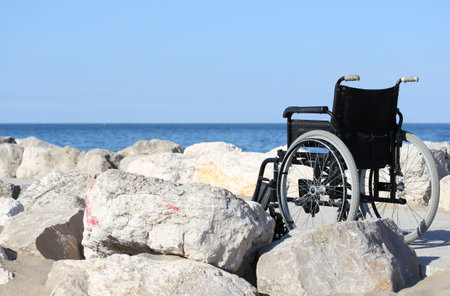 wheelchair black on blue ocean shore in a sunny summer day