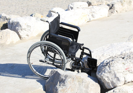 wheelchair stuck on the rocks by the sea in summer