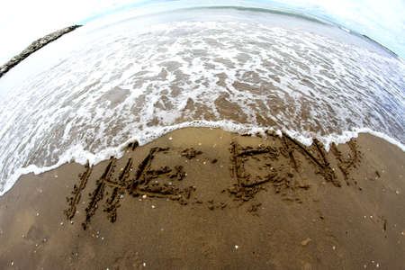 sea wave clears the words THE END on the beach photographed with fisheye lens の写真素材