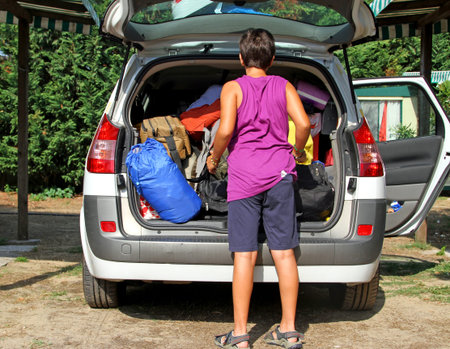 strong boy loads his bags in the car after the holidaysの写真素材