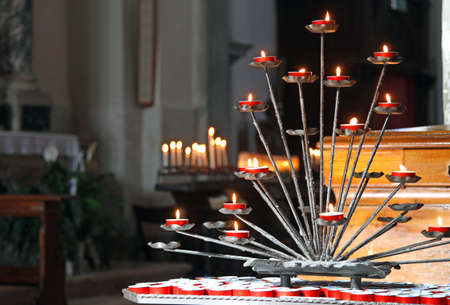 church interior with candelabra and lit candles during the prayers of the faithfulのeditorial素材