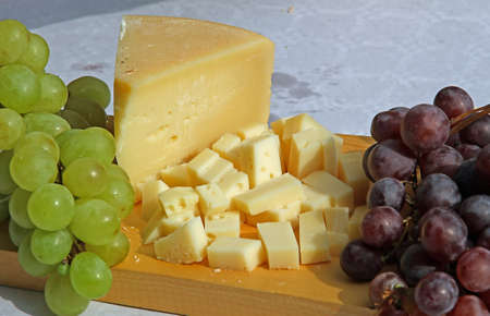 cheese and grapes on the wooden cutting board during a picnic outdoorsの写真素材