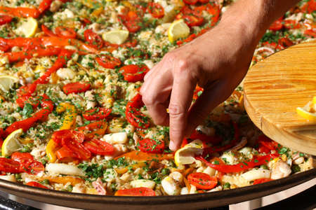 hadn of Cook adds slices of lemon to paellaの写真素材