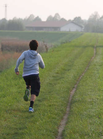 child runs along a country road at sunsetの写真素材