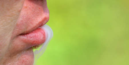 smoker expels the smoke from his mouth after smoking the electronic cigaretteの写真素材