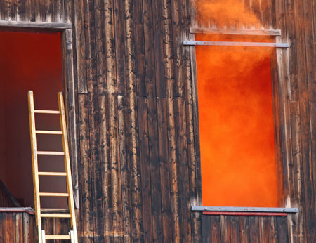 Dense orange smoke comes out of the window and a ladder of the fire nearの写真素材