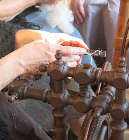 elderly woman who works the wool with an antique spinning wheel