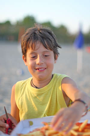 little boy while eating pizza takeaway in Sunset Beachの写真素材