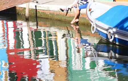 tourists with barefoot into the water on the Burano island near veniceの写真素材