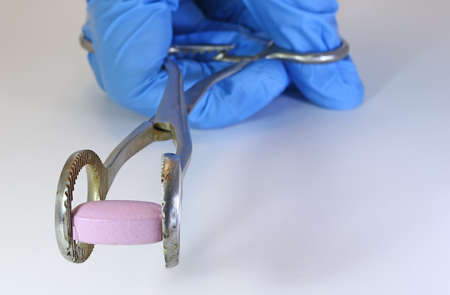 pill with medical forceps and the doctor's blue gloveの写真素材
