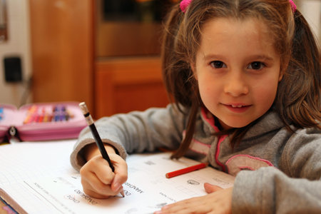 little girl writes the homework on notebook