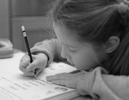 pretty little girl writes on the notebook of schoolworkの写真素材