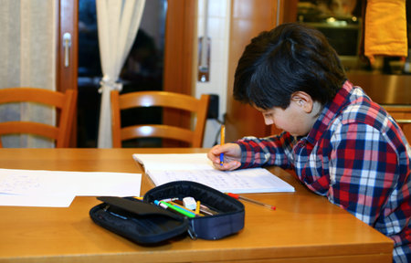 young boy writes on his notebook at home 7