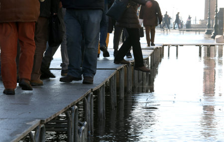 People walkingÂ onÂ theÂ catwalk in Venice Italy during at high tide