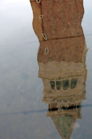 Belltower of Saint Mark in Venice reflected on a puddle at high tideの写真素材