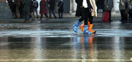 venice people with plastic boots at high tide in St. Mark's squareの写真素材