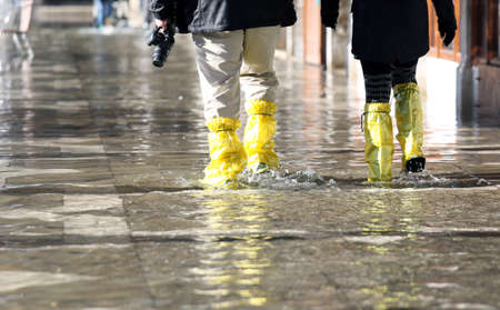 venice photographer with yellowe gaiters at high tide in St. Mark's squareの写真素材