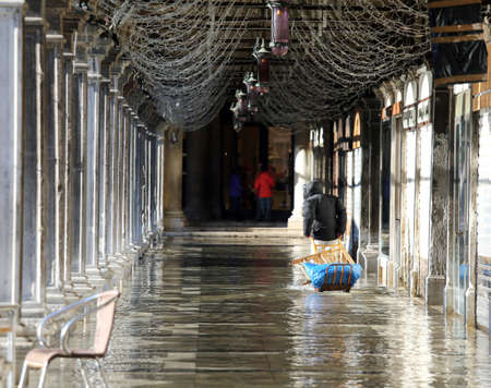 man with the transport cart t at high tide in Veniceのeditorial素材