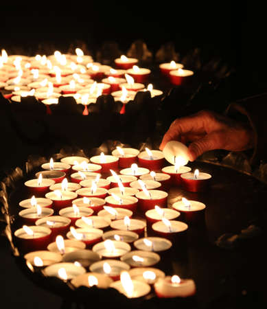 old faithful hand lights a candle in churchの写真素材