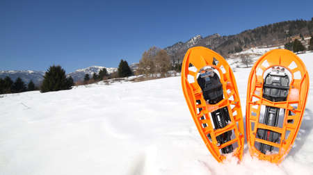 pari of orange modern snowshoes in the mountainの写真素材