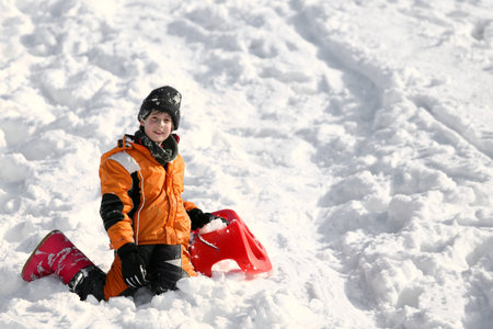 Child plays with sled in the snow in winter in the mountains