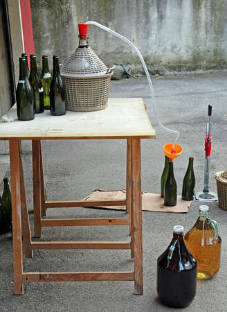 homemade bottling red wine in glass bottles with an orange funnelの写真素材