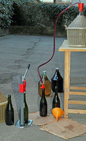 homemade bottling red wine in glass bottles with an orange funnelの写真素材