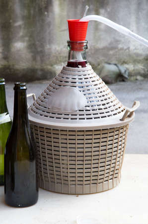 homemade wine bottling in the backyard with the Carboy and glass bottlesの写真素材