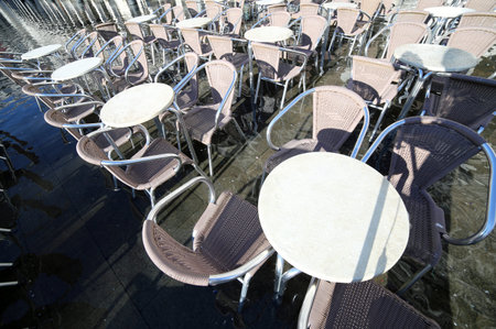 Venice, chairs and table of snack bar with water at high tide