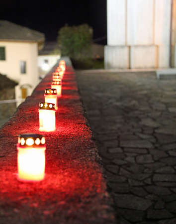 long line of Red candles in the churchyard during mass outdoors at nightの写真素材
