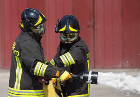 two firemen in action with foam to put out the fire