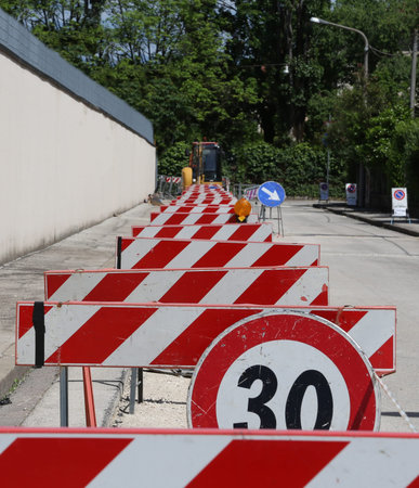 speed limit sign and hurdles in the road excavation for the laying of optical fibre